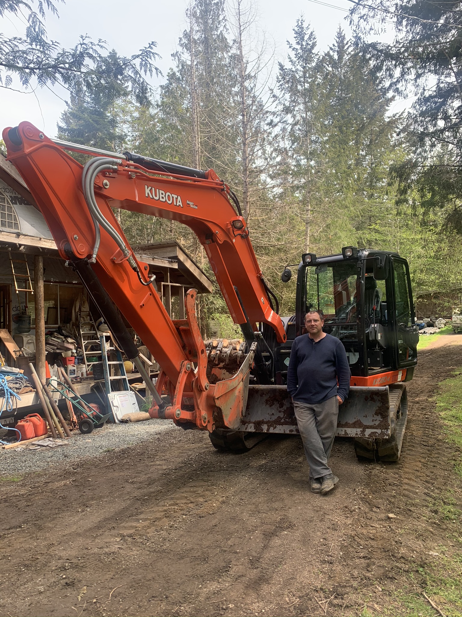 Dorian Baker standing next to a Kubota KX080-4 excavator